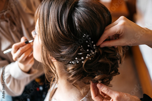 A hair stylist and make-up artist prepare a bride for the wedding day