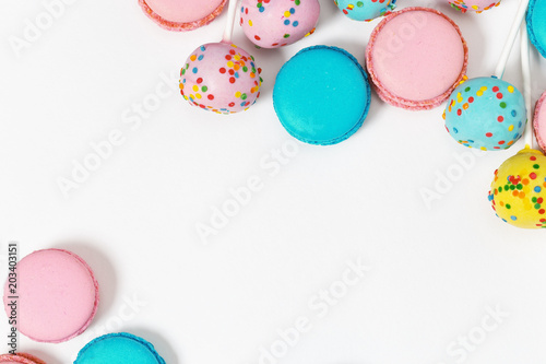 Pink and mint blue macaroons and colorful cake pops. Delicious multi-colored almond cookies as background. Copy space. Top view.