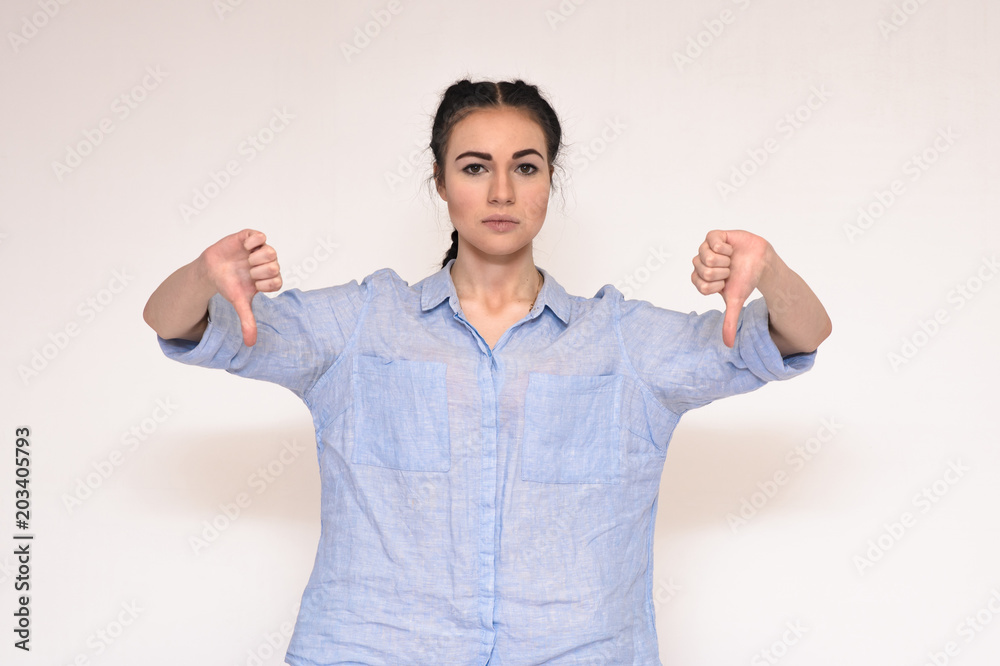 Portrait of a beautiful brunette girl on a gray background showing down Portrait of a beautiful brunette girl on a gray background showing down