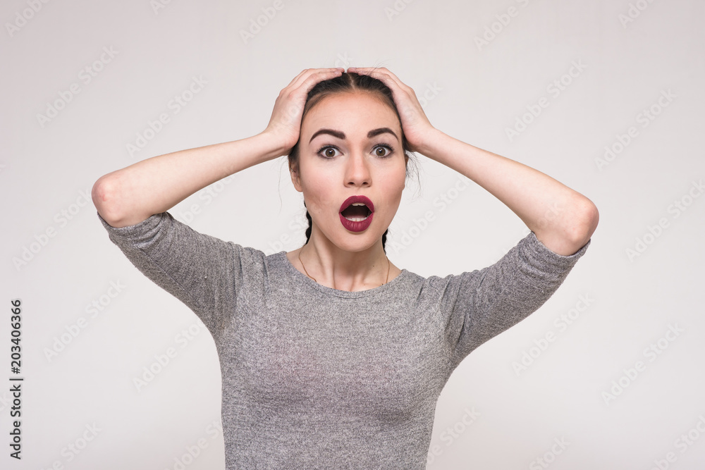 Portrait of a beautiful brunette girl on a gray background brightly showing emotions Portrait of a beautiful brunette girl on a gray background brightly showing emotions