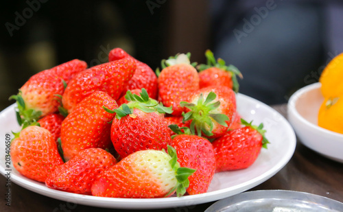 Fresh srawberries in white ceramic plate on dark background photo
