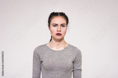 Bilde på lerret Portrait of a beautiful brunette girl on a white background showing displeasure