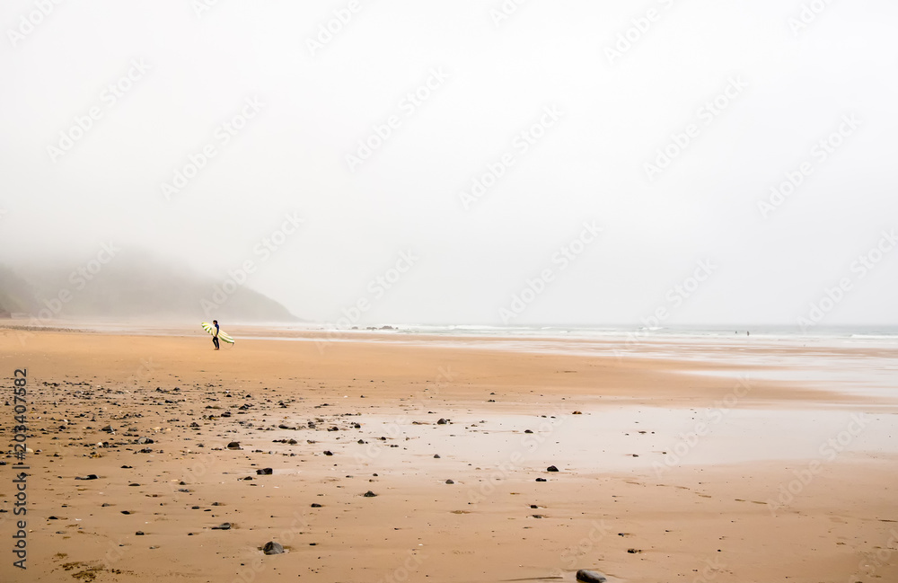 surfer on the beach a day of rain and fog surfer on the beach a day of rain and fog