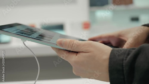 sale, consumerism, technology and people concept - happy young man choose tablet pc computer electrinic shop pointing finger in mall photo