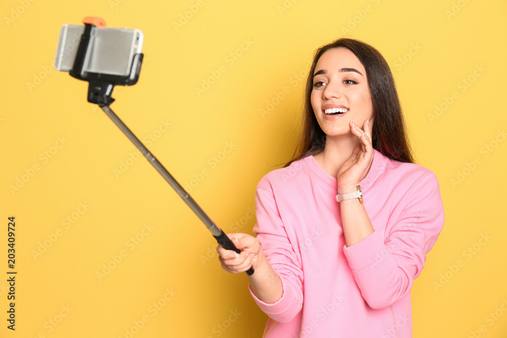 Young beautiful woman taking selfie against color background Young beautiful woman taking selfie against color background