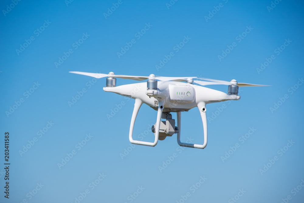 The modern drone, quadrocopter is in the air against the background of the sky and grass The modern drone, quadrocopter is in the air against the background of the sky and grass