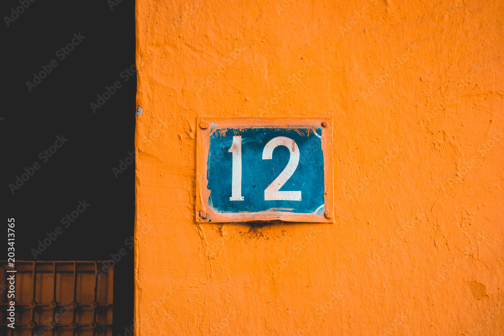 blue number 12 door sign on orange facade blue number 12 door sign on orange facade