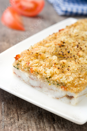 White fish casserole with cheese on wooden background.