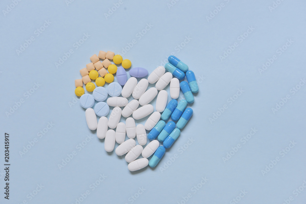 Healthcare and medical series - heart shape of medicine pills, tablets and capsules on background Healthcare and medical series - heart shape of medicine pills, tablets and capsules on background