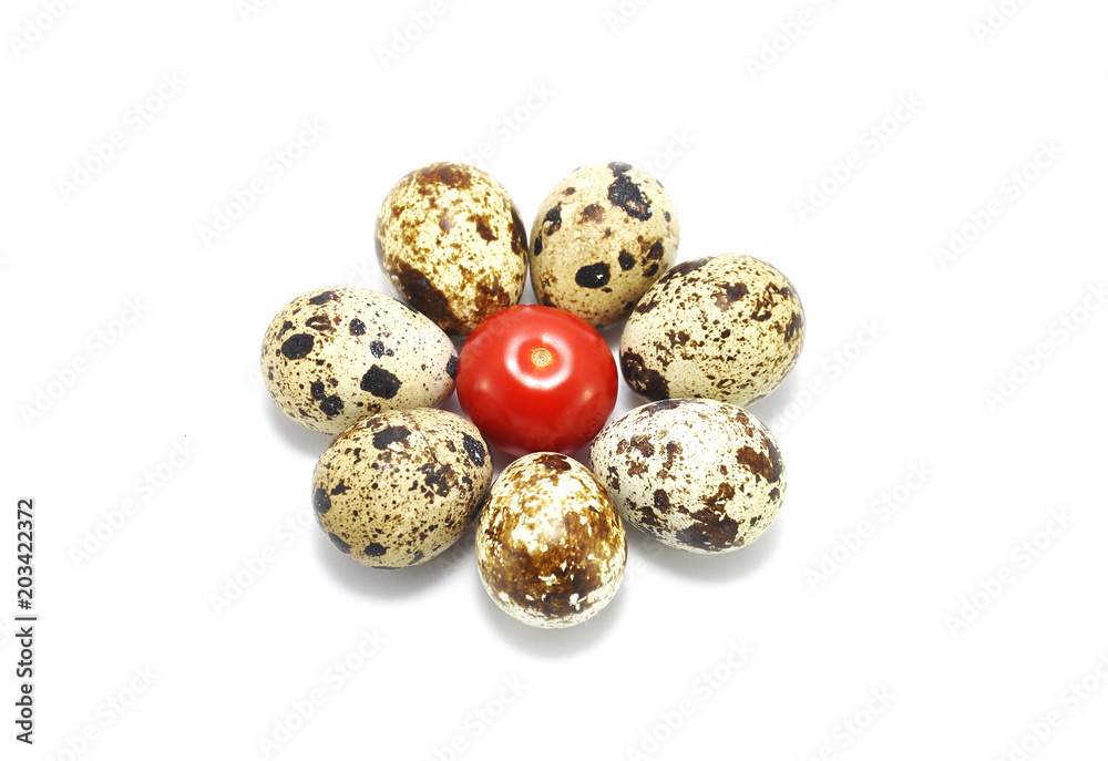 Quail eggs and red tomato on white closeup background