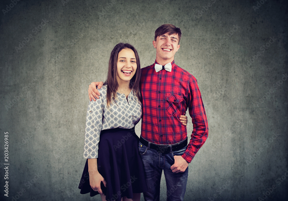 Cheerful young woman and man embracing one another, looking and smiling at camera Cheerful young woman and man embracing one another, looking and smiling at camera