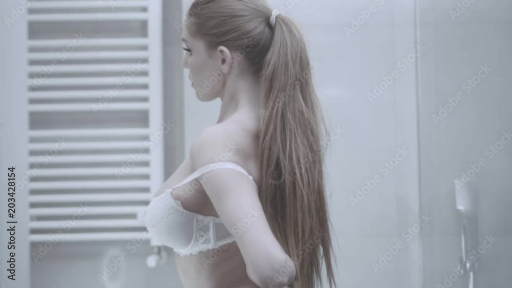 Sensual sexy woman taking off bra and walking to the bathroom Sensual sexy woman taking off bra and walking to the bathroom