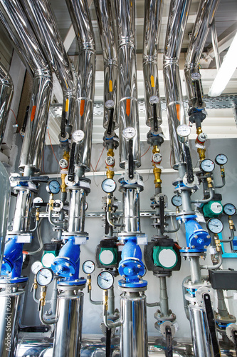 The interior of an industrial boiler house with a multitude of pipes, barrels and sensors