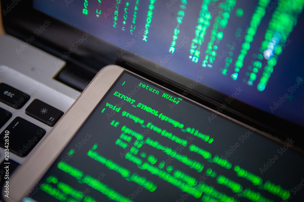 Multi screen runing command. Hacker working with multi computer device. On the table have personal computer, laptop and mobile. On screen showing binary code Multi screen runing command. Hacker working with multi computer device. On the table have personal computer, laptop and mobile. On screen showing binary code