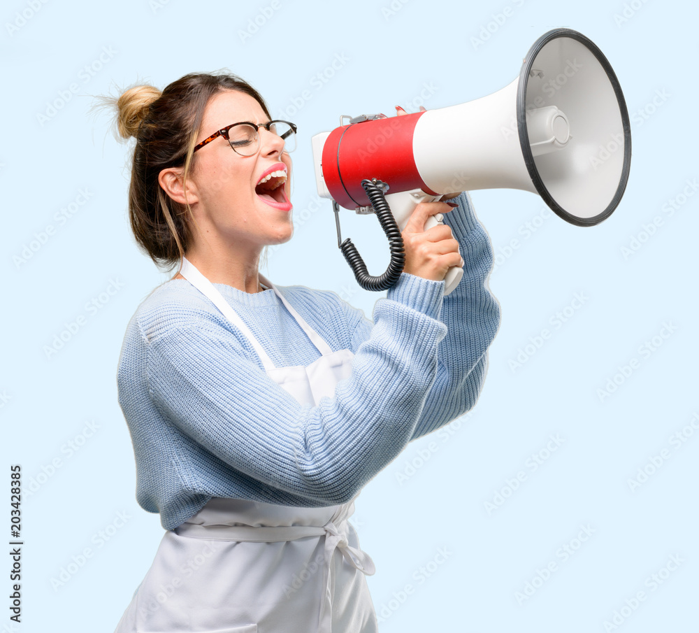 Young woman shop owner, wearing apron communicates shouting loud holding a megaphone, expressing success and positive concept, idea for marketing or sales Young woman shop owner, wearing apron communicates shouting loud holding a megaphone, expressing success and positive concept, idea for marketing or sales