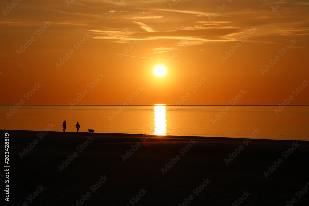 Sonnenuntergang am Meer Paar mit Hund als Silhouette im Vordergrund Sonnenuntergang am Meer Paar mit Hund als Silhouette im Vordergrund