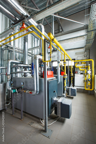 The interior of an industrial boiler house with a multitude of pipes, boilers and sensors