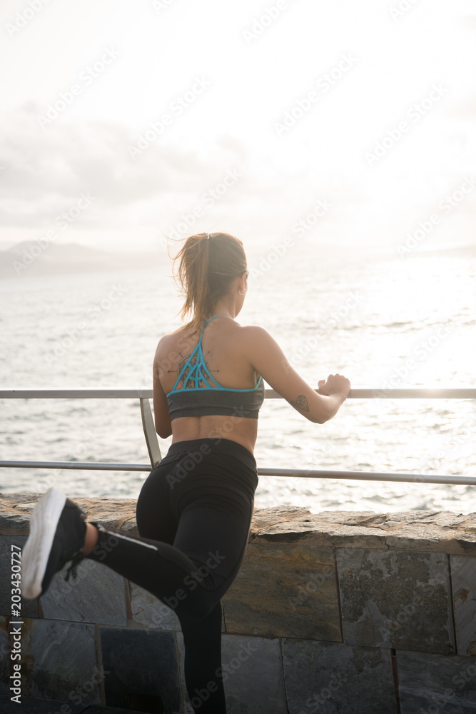 Fit young woman holding onto railing Fit young woman holding onto railing