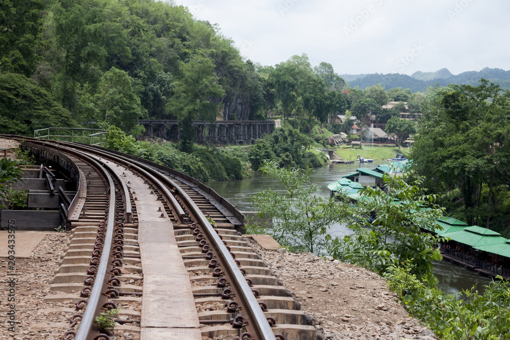 Fototapeta premium Railroad tracks above the trees near the cliff with nature of river of history from World War 2 at Death Railway Kanchanaburi Province Thailand.