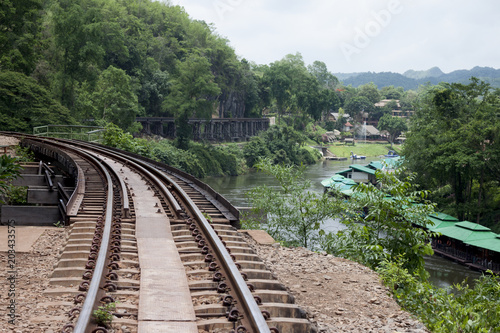 Railroad tracks above the trees near the cliff with nature of river of history from World War 2 at Death Railway Kanchanaburi Province Thailand.