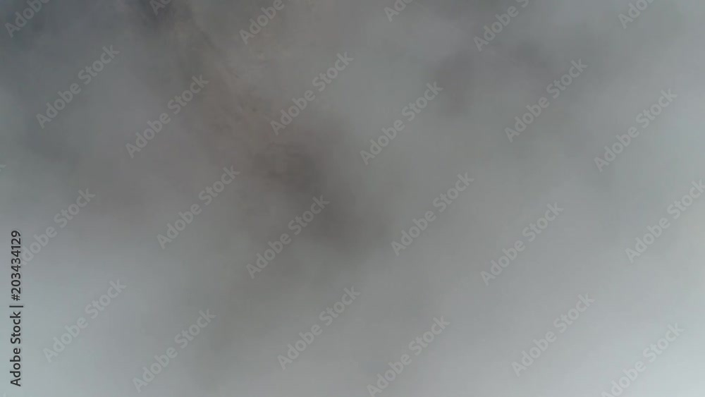 Aerial top down view of volcanic landscape first showing thick clouds then showing cooled down lava flows and in between the fertile soil with vegetation on landscape also showing road to Mount Etna Aerial top down view of volcanic landscape first showing thick clouds then showing cooled down lava flows and in between the fertile soil with vegetation on landscape also showing road to Mount Etna