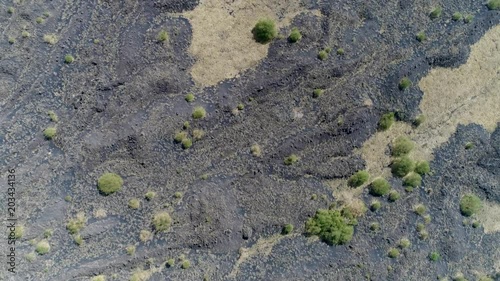 Aerial top down view flight over volcanic landscape showing the cooled down lava flows and in between the fertile soil with vegetation on landscape located at Sicily Italy Mount Etna 4k quality photo