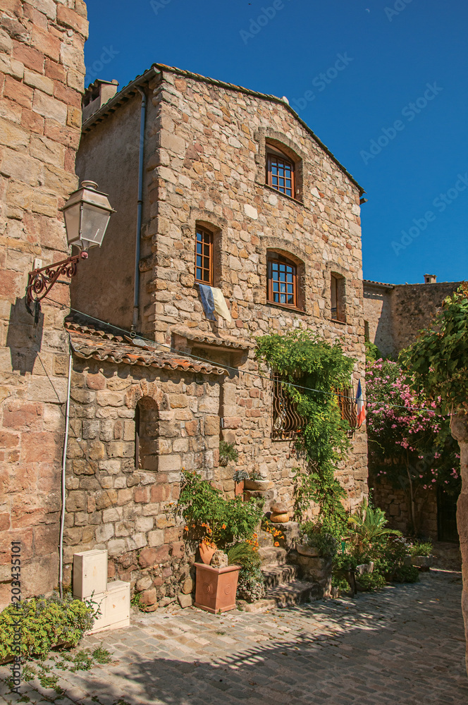 Close-up of stone house facade with bindweed in an alley, at the gorgeous medieval hamlet of Les Arcs-sur-Argens, near Draguignan. Located in the Provence region, Var department, southeastern France