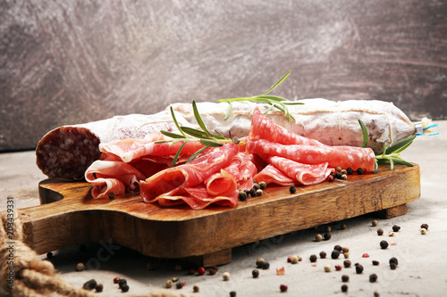 Food tray with delicious salami, prosciutto crudo, fresh sausages and herbs. Meat platter with selection
