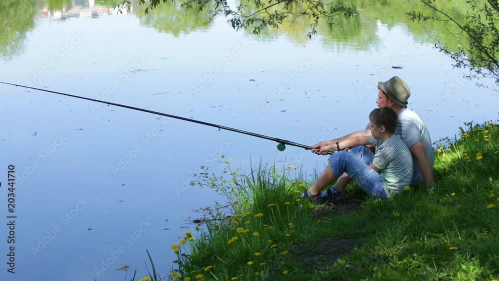 Happy family on summmer vacations concept. Father and son fishing together at river bank. Real time full hd video footage. Happy family on summmer vacations concept. Father and son fishing together at river bank. Real time full hd video footage.