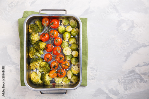 Oven baked vegetables with spices and herbs on baking tray. Grilled brussel sprouts, cherry tomatoes and broccoli. Top view, copy space.