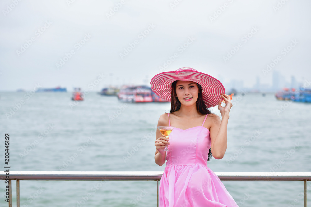 Holiday concept. Beautiful girl is happy to celebrate. Beautiful girl holding a glass of wine on the beach. Beautiful girl smiling with joyous emotions.