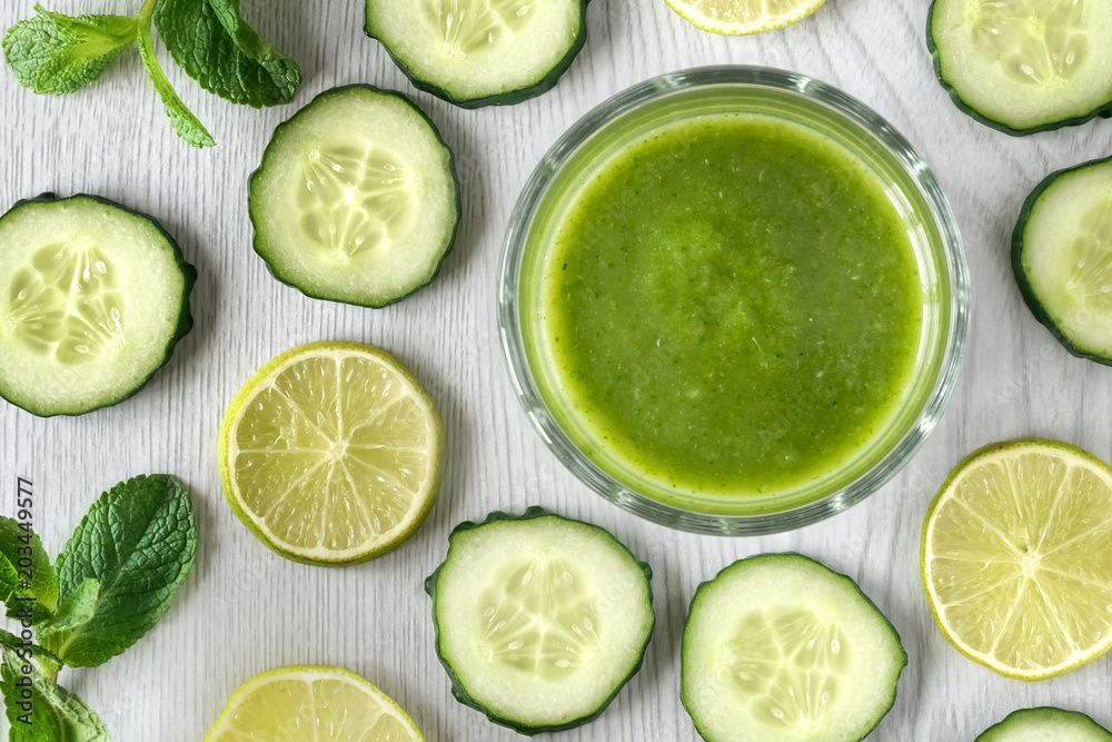 Healthy green cocktail with cucumber, lemon, spinach and mint in a glass cup on a white wooden background Healthy green cocktail with cucumber, lemon, spinach and mint in a glass cup on a white wooden background