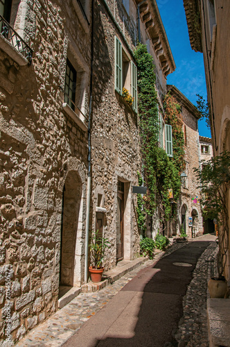 View of alley with stone houses on a blue sunny day in Saint-Paul-de-Vence, a lovely well preserved medieval hamlet near Nice. In Alpes-Maritimes department, Provence region, southeastern France © Celli07
