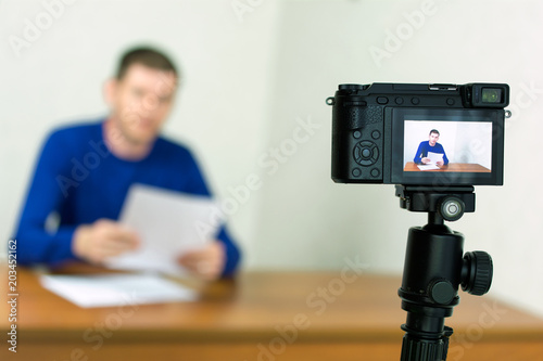 Young man recording video using a tripod mounted digital camera. fake news concept