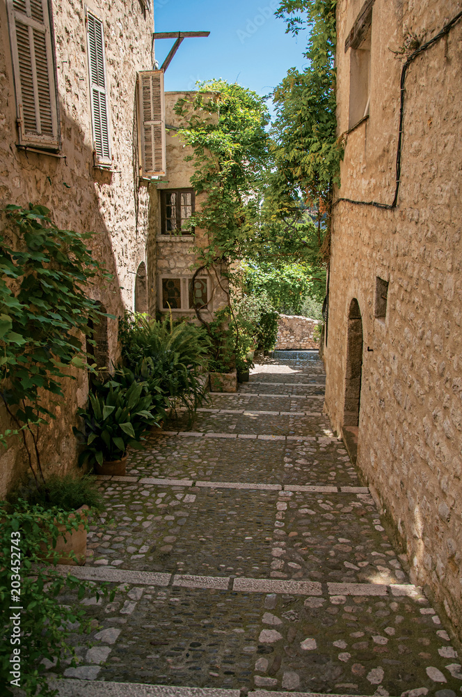 View of alley with stone houses and slope in Saint-Paul-de-Vence, a lovely well preserved medieval hamlet near Nice. Located in Alpes-Maritimes department, Provence region, southeastern France