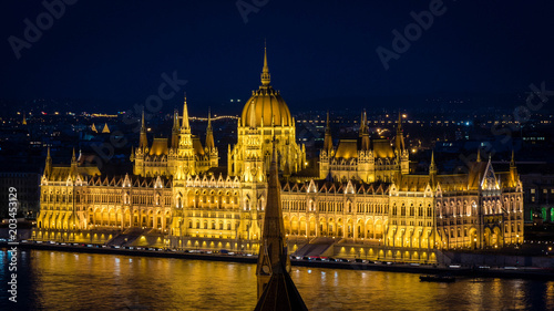 Golden Parliament of Budapest at night up close seen from opposite river bank
