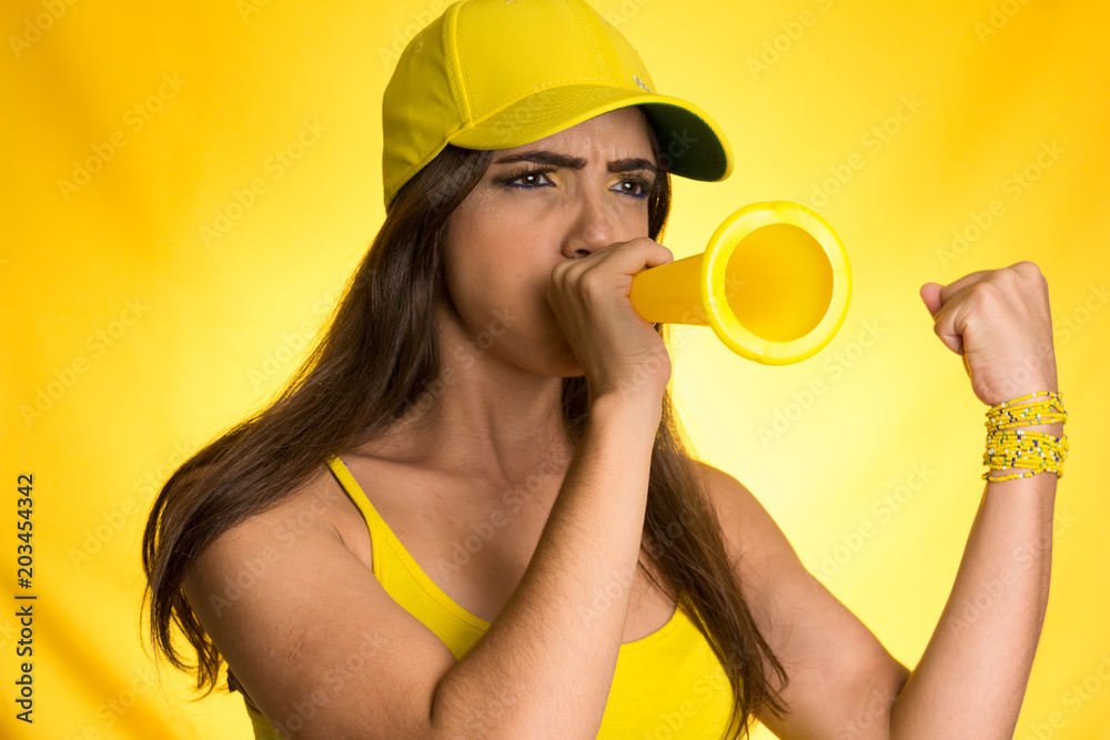 Brazilian woman fan celebrating on football match on yellow background. Brazilian woman fan celebrating on football match on yellow background.