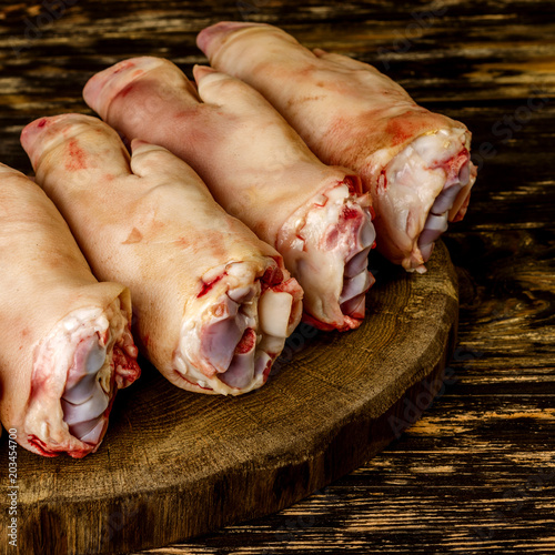 Raw and freesh pork feet or legs,over dark wooden board. They are stacked pile. Food meat shot.