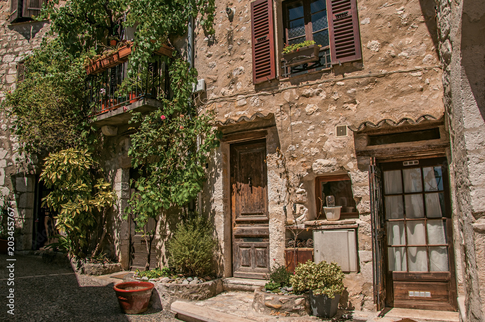 Alley view with wooden doors and plants in Saint-Paul-de-Vence, a lovely well preserved medieval hamlet near Nice. Located in Alpes-Maritimes department, Provence region, southeastern France