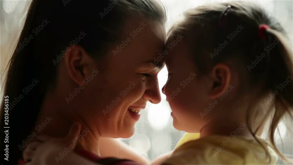 Mother and Her Daughter are Cuddling. Rain is on Background. They Are Having a Lot of Fun Because Today is Mother's Day. Mother and Her Daughter are Cuddling. Rain is on Background. They Are Having a Lot of Fun Because Today is Mother's Day.
