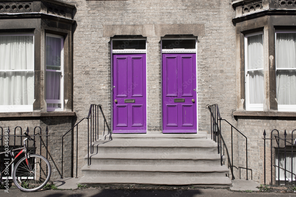 Two identical pink purple wooden front doors at the entrance of a classic Victorian british style house