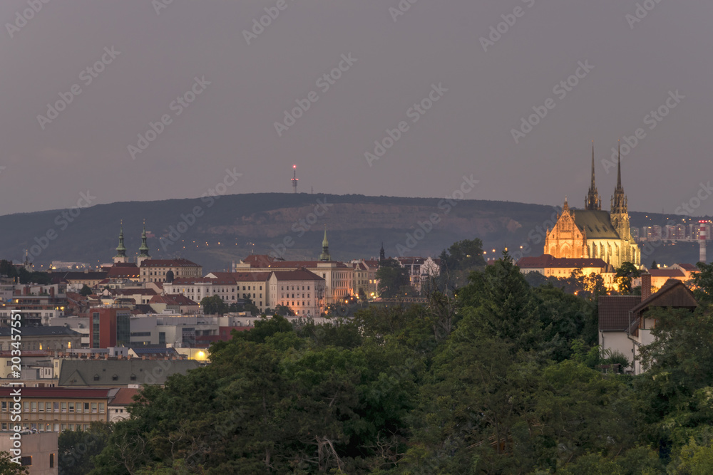 Evening view on Brno city. Buildings, saint Paul and Peter cathedral lighting at night with quarry Hady and communication tower on background.