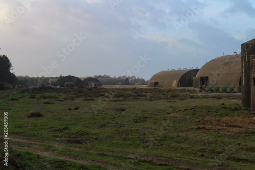 Wide view of abandoned Rendlesham Air Force base hangers which are now overgrown