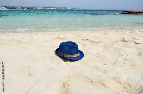 Blue color of sea, white sand and straw hat on beach. Holiday relaxing, beach vacation concept. Copy space. Place for text