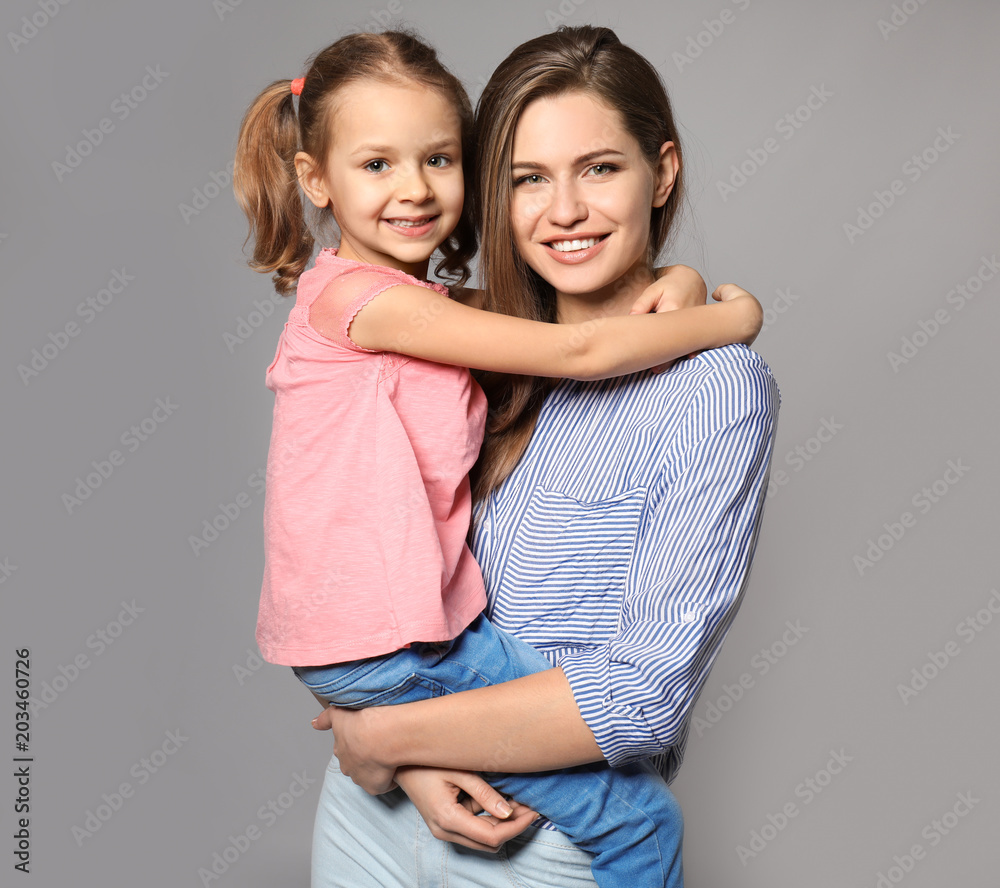 Portrait of mother and cute little daughter on grey background Portrait of mother and cute little daughter on grey background