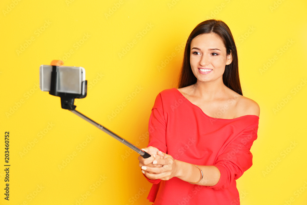 Young beautiful woman taking selfie against color background Young beautiful woman taking selfie against color background