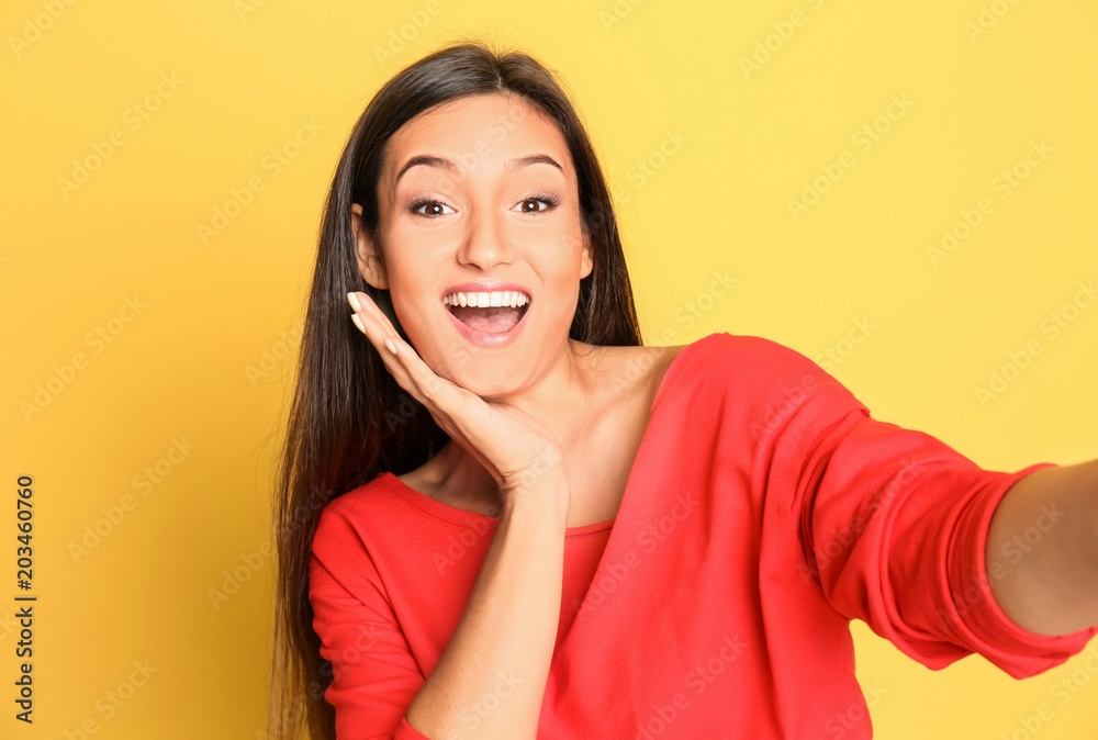 Young beautiful woman taking selfie against color background Young beautiful woman taking selfie against color background