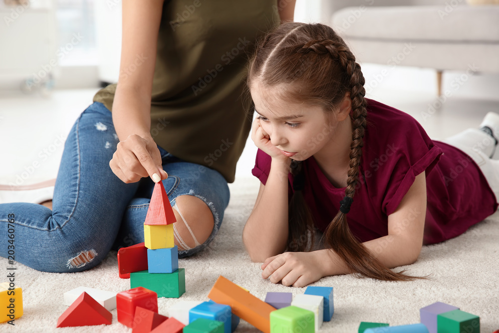 Young woman and little girl with autistic disorder playing at home Young woman and little girl with autistic disorder playing at home