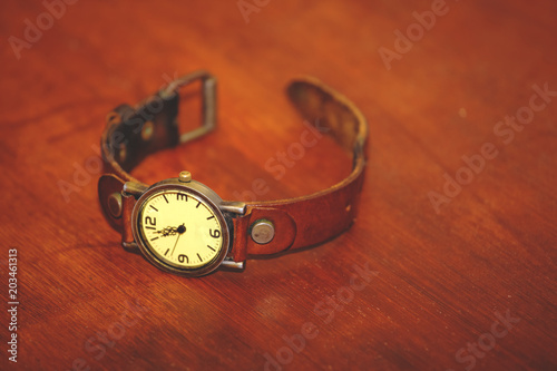 small wristwatch with leather strap on the table, retro toned