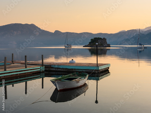 Small boats in the sunrise reflected in the hills